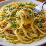 italian pasta with garlic olive oil sauce served on a plate close up showing the golden garlic infused olive oil coating the pasta strands