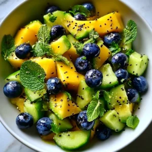 Juicy mango cucumber salad topped with blueberries and avocado in a bowl